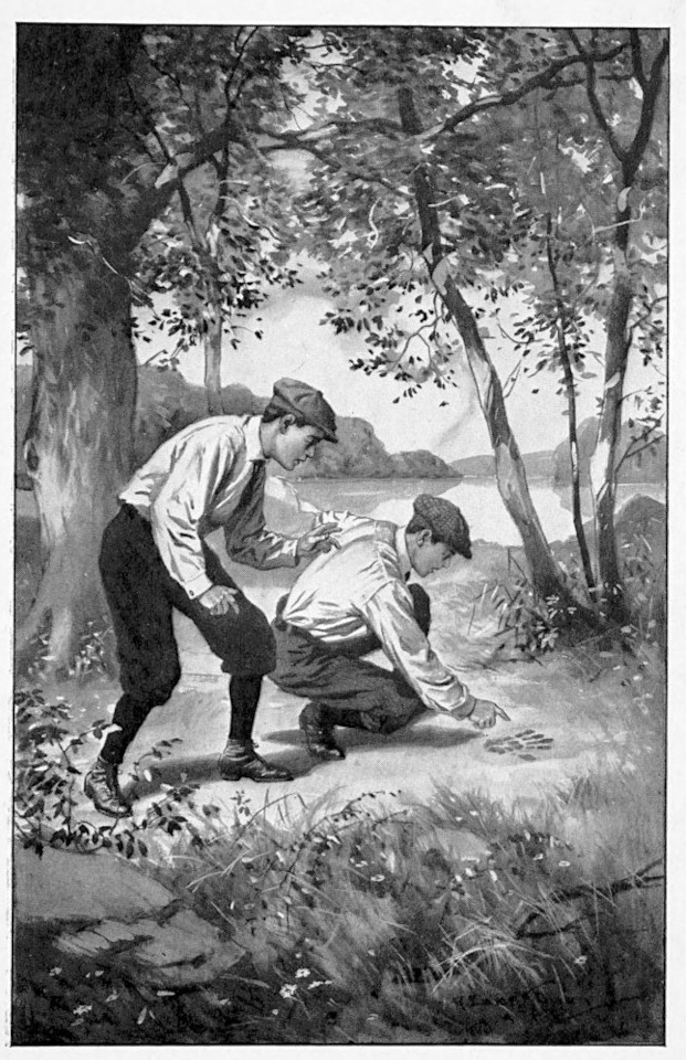 Two boys crouched looking at a
footprint.
